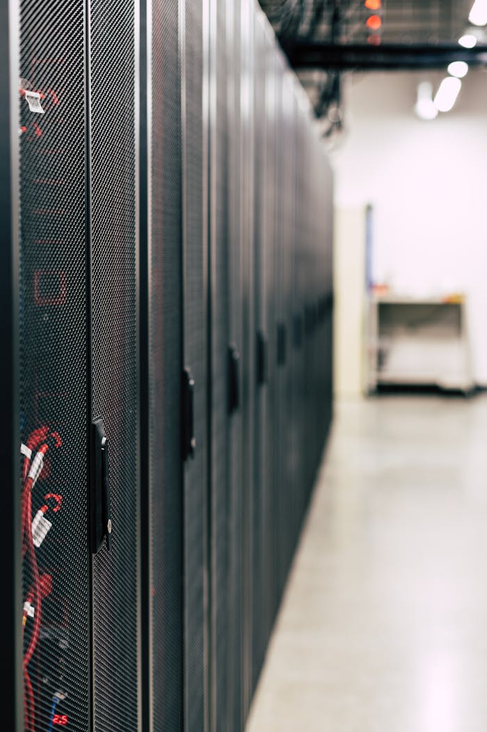 services-02 Metal black cabinets with servers inside with red wires connected standing in row in lighted room